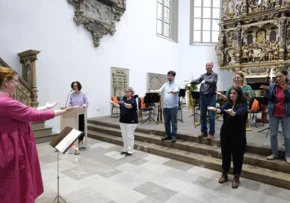 Claudia Oelze dirigiert den Gebärdensprachchor. | Foto: Screenshot (Bearbeitung): Dorothee Schneider